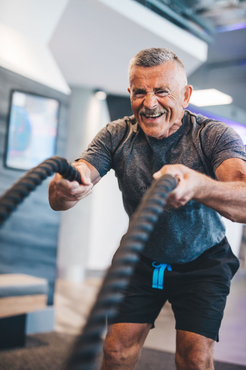 Active older man training with battle ropes at the gym, symbolizing strength, energy, and vitality after testosterone therapy.