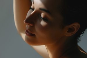 Lovely young woman with dark hair and eyes closed in sunlight. Beauty and elegance, skincare and morning moods
